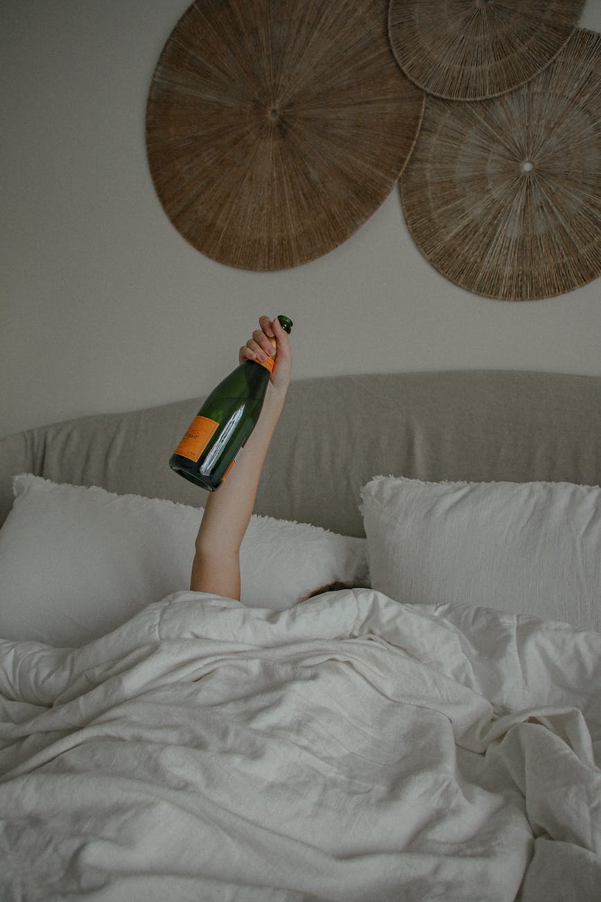 a woman holding a champagne bottle while in bed